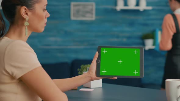 Back View of Woman Holding Tablet Computer with Mock Up Green Screen