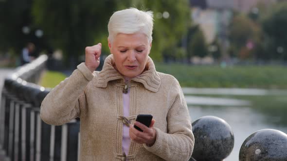 Euphoric Grayhaired Mature Woman Looking at Cellphone Screen Reading Sms with Unexpected Excellent