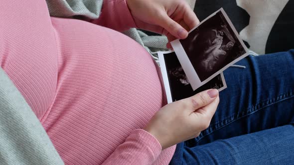 Pregnant woman touching her belly while viewing ultrasound scans at home, pregnancy, and childbirth