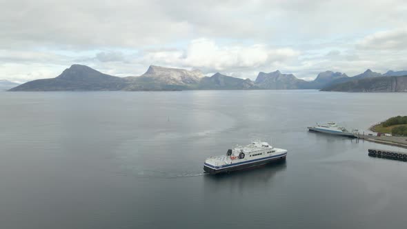 Aerial shot of a ferry sailing on the coast of Norway surrounded by mountains