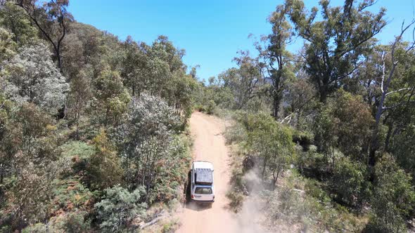 Aerial Drone Shot of 4WD Driving up Dirt Road Emerging to show Blue Water and Mountains near Lake Ei