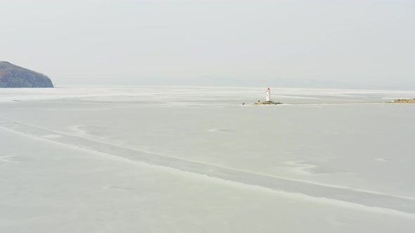 Flight Over the Frozen Sea and Drone View of Tokarevsky Lighthouse at Dawn