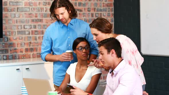 Businesspeople interacting while using laptop