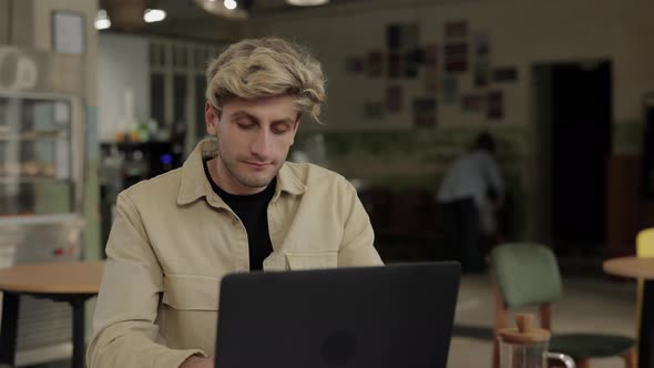 Handsome Guy Sitting at Cafe and Working on Laptop