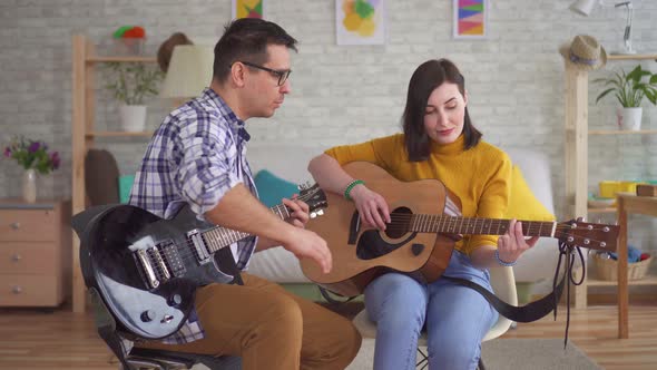 Young Man Guitarist Teaches a Young Woman To Play Guitar