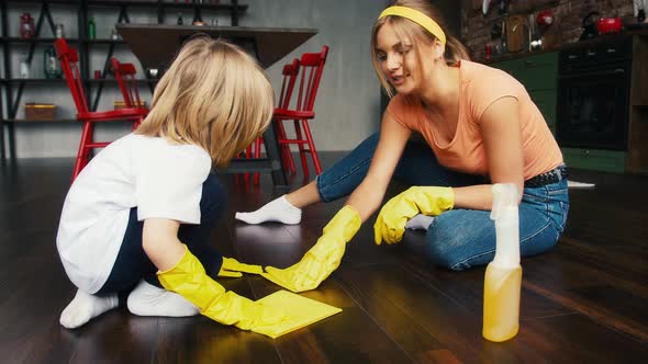 Mom and Her Kid in Yellow Rubber Gloves and Casual Outfit are Smiling and Talking Cleaning Floor By