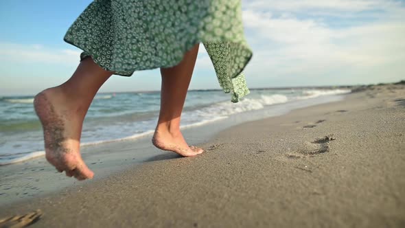 Legs of a Young Woman in Slow Motion Walking Barefoot on the Beach