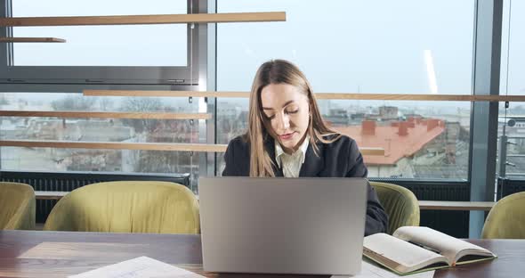 Concerned Woman Working on Laptop Computer and Looking Away Thinking Solving Problem at Office