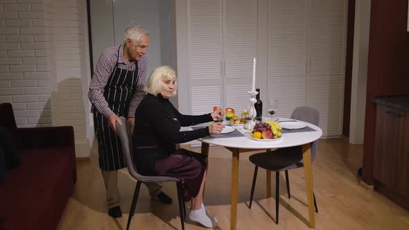 Senior Retired Couple Having Fun During Romantic Supper in the Kitchen Celebrating Their Anniversary