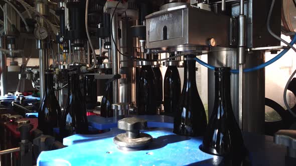 Putting stoppers on filled up wine bottles. These bottles are on a conveyor belt.