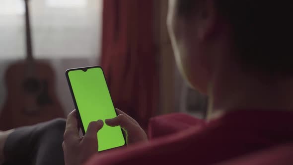 Back View of Woman Holding Chroma Key Green Screen Smartphone