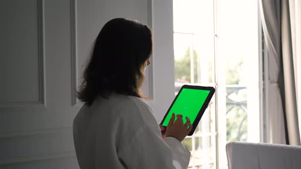 Woman Uses Tablet PC with Green Screen in Hotel