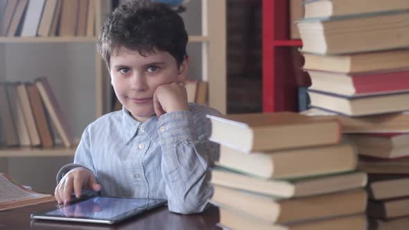 happy schoolboy at his Desk looks at the camera and laughs.