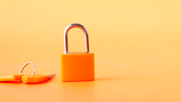 Orange Color Padlock And Key on Table