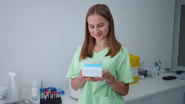 Portrait of Confident Charming Laboratory Assistant Posing with Box of Test Tubes Indoors