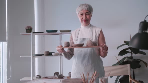 Asian elderly woman enjoying pottery work at home.