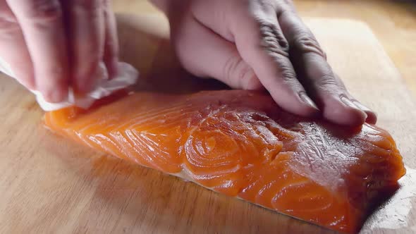 Close Slow Motion Shot of Patting a Salmon Fillet Dry With Paper Towels Prior to Cooking in the Kitc