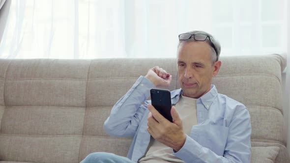 Elderly Man Rejoices Looking Into Smartphone