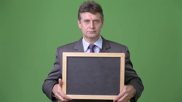 Mature Handsome Businessman Against Green Background