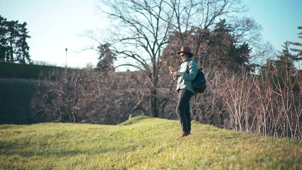 A Beautiful Middleaged Woman Uses Her Phone While Walking in a Spring Park