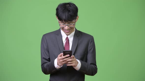 Young Happy Asian Businessman Smiling While Using Phone