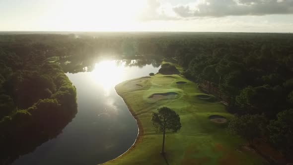 Drone flying over golf course with water and ponds in early morning