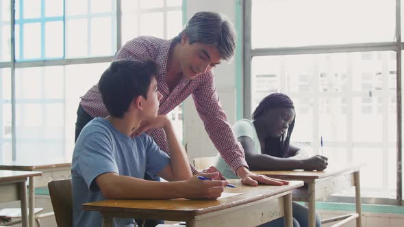 Male Teacher Checking Multi Ethnic Classroom Test