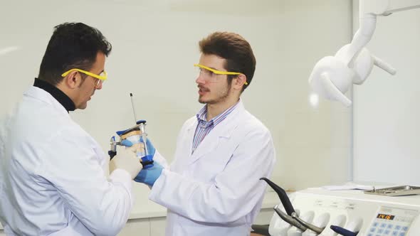 Young Male Dentist Working with His Colleague Examining Dental Mold