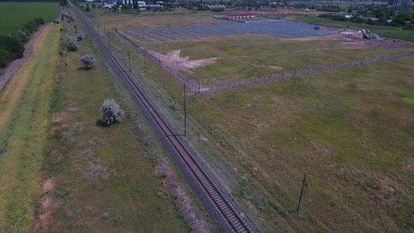 Railroad Tracks Near a Solar Power Station in the Field Aerial Footage