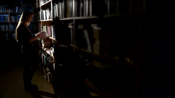 Pretty Young College Student in a Library, Chooses a Book