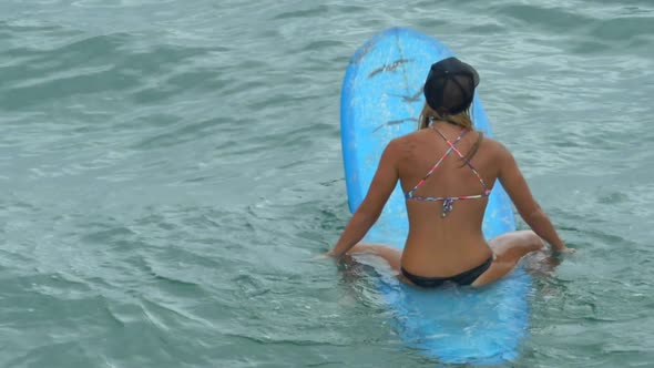 A young woman surfing in a bikini on a longboard surfboard.