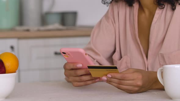 Cute African American Woman Makes an Online Purchase Using a Credit Card and Smartphone