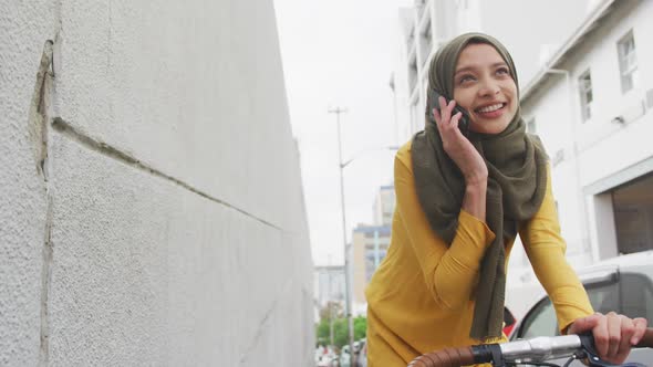 Woman wearing hijab having a phonecall on a bike