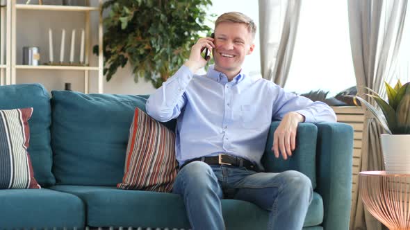 Middle Aged Man Talking on Phone Sitting on Couch