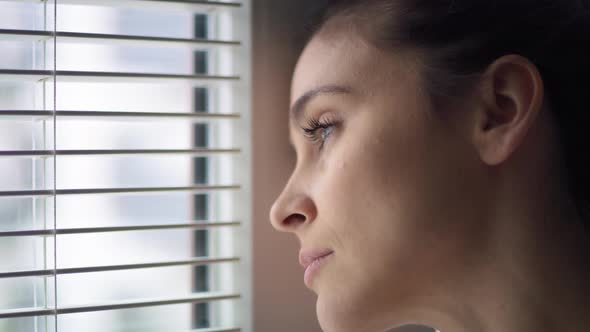 Close up of sad woman looking out the window. Shot with RED helium camera in 8K.