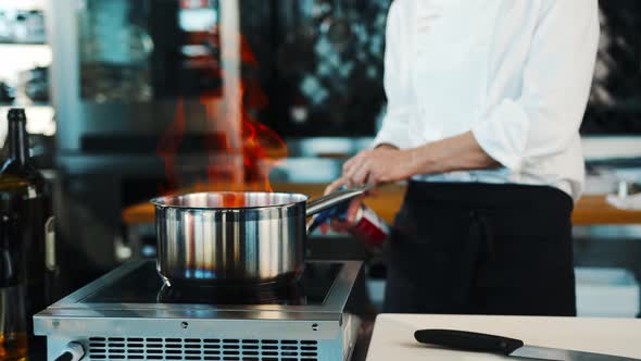 The chef sets fire to the dish in the professional kitchen of the restaurant. The process of cooking