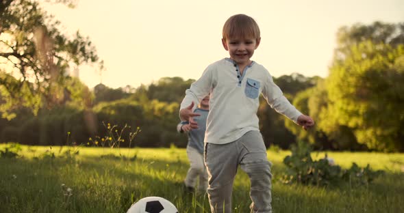 In Slow Motion a Happy Boy with a Soccer Ball Runs Into the Field at Sunset Dreaming of Playing