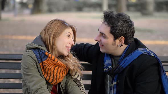 Smiling happy lovers talking sitting on public park bench.First date,flirt