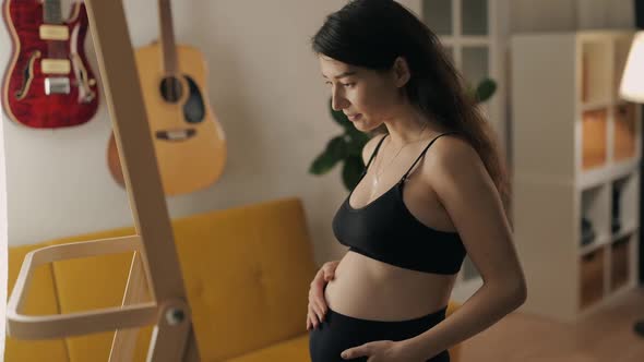 Pretty Multiracial Pregnant Woman Wearing Underwear Looking at Mirror