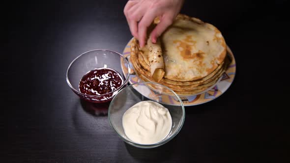 girl twists a pancake and dips it in sour cream