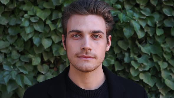 Slow motion shot of young man in front of a wall with climbing plants