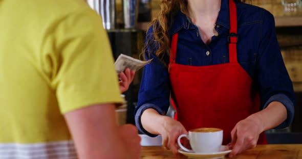 Female costumer paying bill to waitress at counter