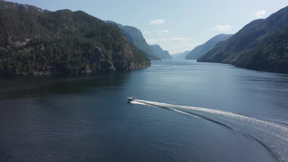 Shot from above, speed boat cruising in Norwegian fjord, idyllic landscape