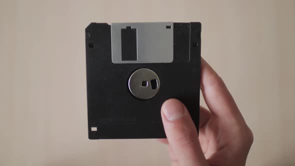Male Hand Holds Up Black Floppy Disk