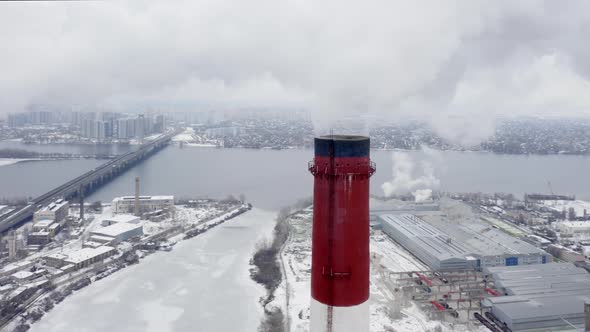 Aerial Survey Over the Tops of Two Smoking Factory Pipes and the Snow-capped City Lying Below