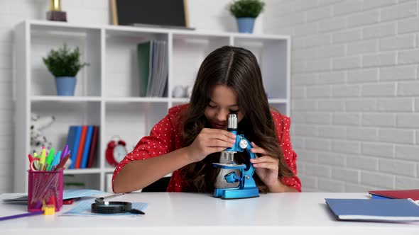 Child Looking Through the Microscope at School Biology