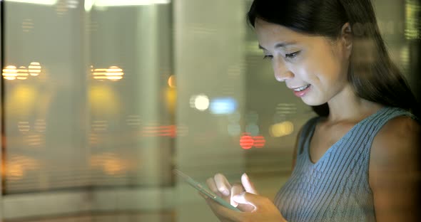 Woman using smart phone in Hong Kong city at night 