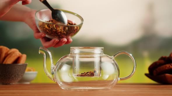 Putting Dry Tea Leaves Into Teapot on a Wooden Table