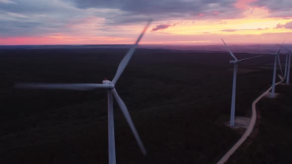 Wind Turbine Farm on Beautiful Purple Evening Mountain Landscape. Renewable Energy Production for