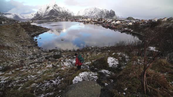 Hiker Clambering Down Hill Towards Reine